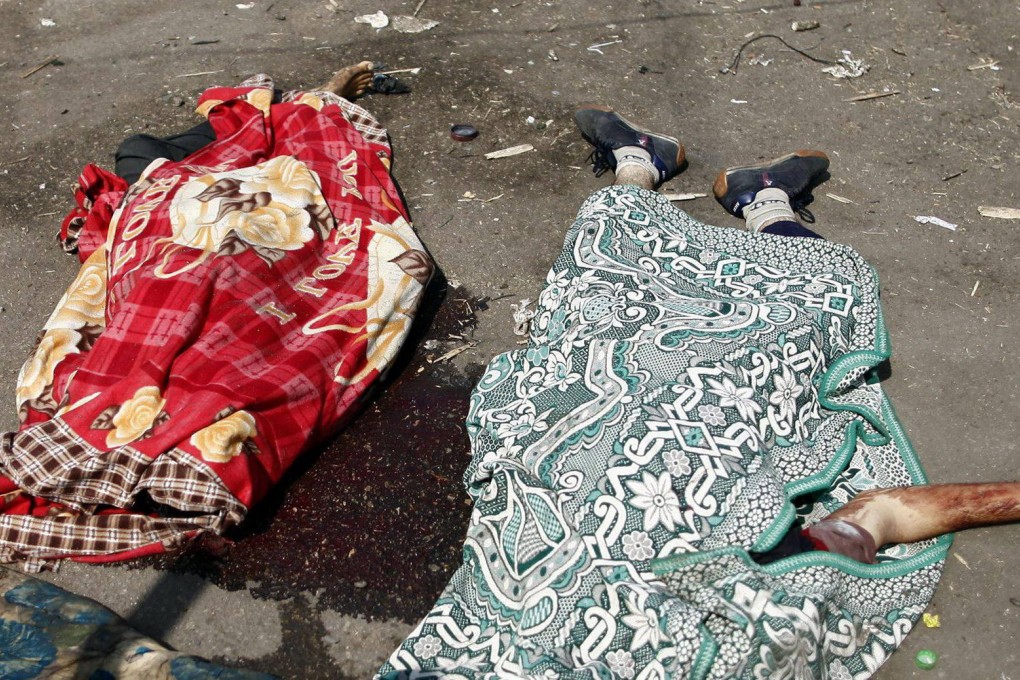 The bodies of two supporters of ousted president Mohammed Mursi lie, covered in blankets, in a pool of blood near the Rabaa al-Adawiya mosque after the swoop by security forces on the protest camp. Photo: AFP