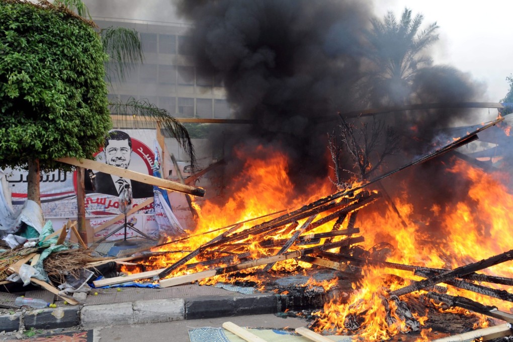 Smoke rises as a tent burns at one of the two sites of the sit-in by the Egyptians supporting ousted leader  Morsi at Nahda square near Cairo University in Cairo. Photo: EPA