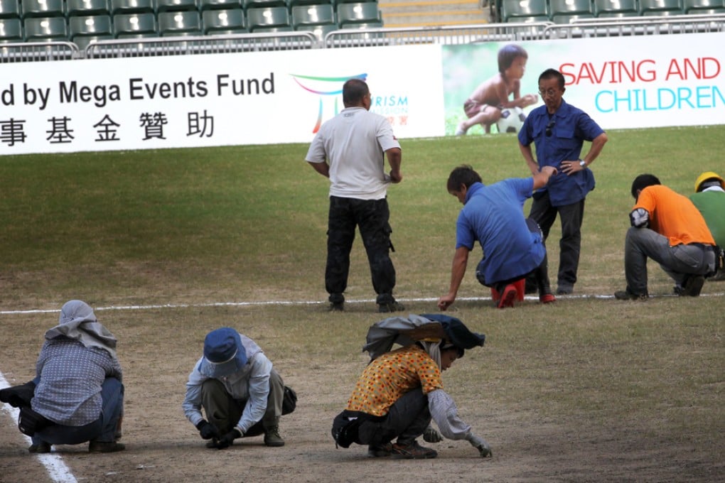 Ground staff try to repair the damaged pitch. Photo: May Tse
