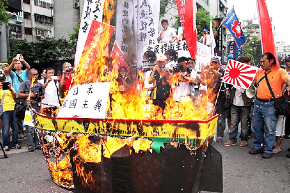 Protesters burn an effigy representing a Japanese warship during a protest in front of Japan's representative office in Taipei, on Thursday. Photo: EPA