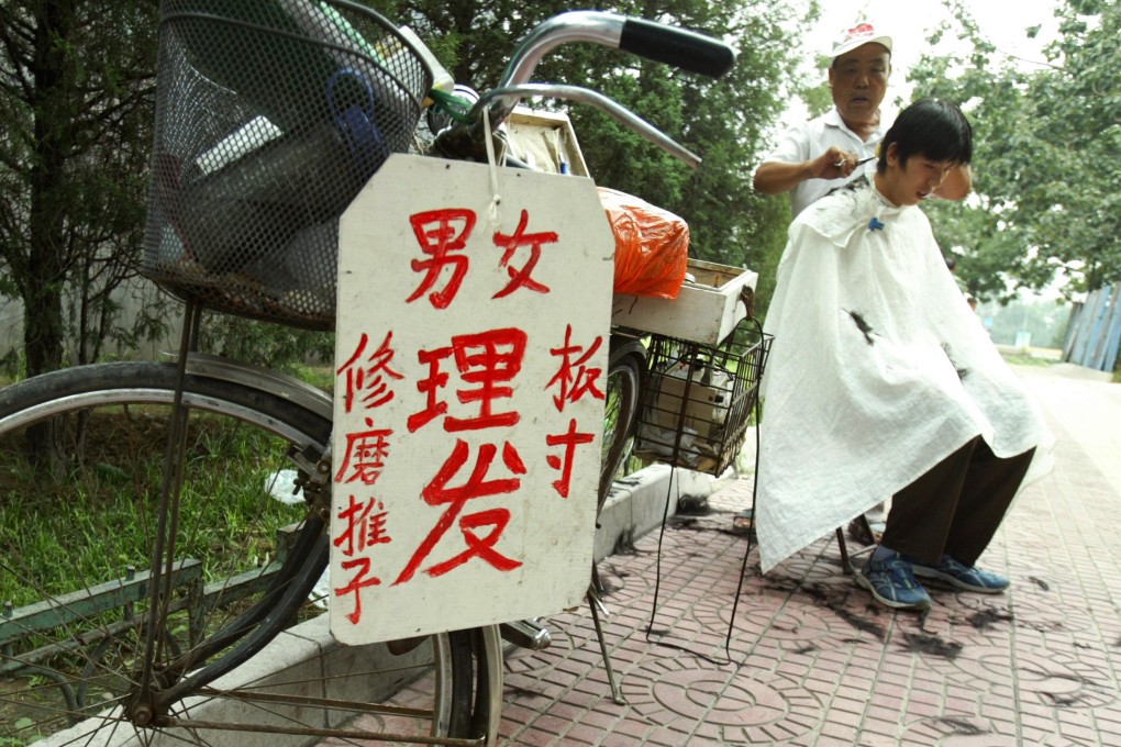 A barber gives a haircut from his mobile bicycle salon on a street in Beijing. Photo: AFP