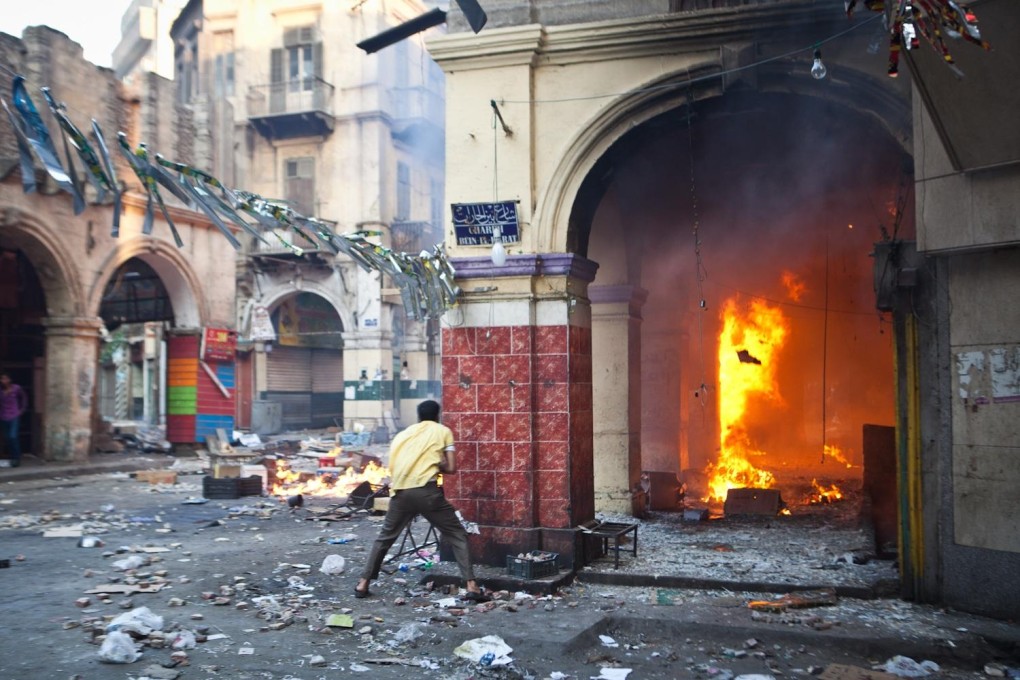 A supporter of the Muslim Brotherhood takes cover during clashes with the military close to Ramses Square in Cairo. Photo: AFP