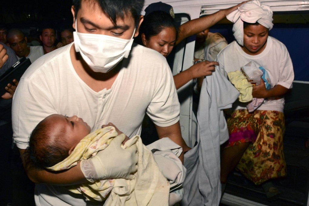 A medic carries three-month-old Trisia Mae Kumaro after the rescue of her and her mother (right) on Friday. Photo: AFP
