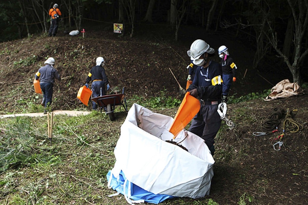 Decontamination workers remove radiated soil and leaves from a forest in Kawauchi, Fukushima. Photo: Reuters
