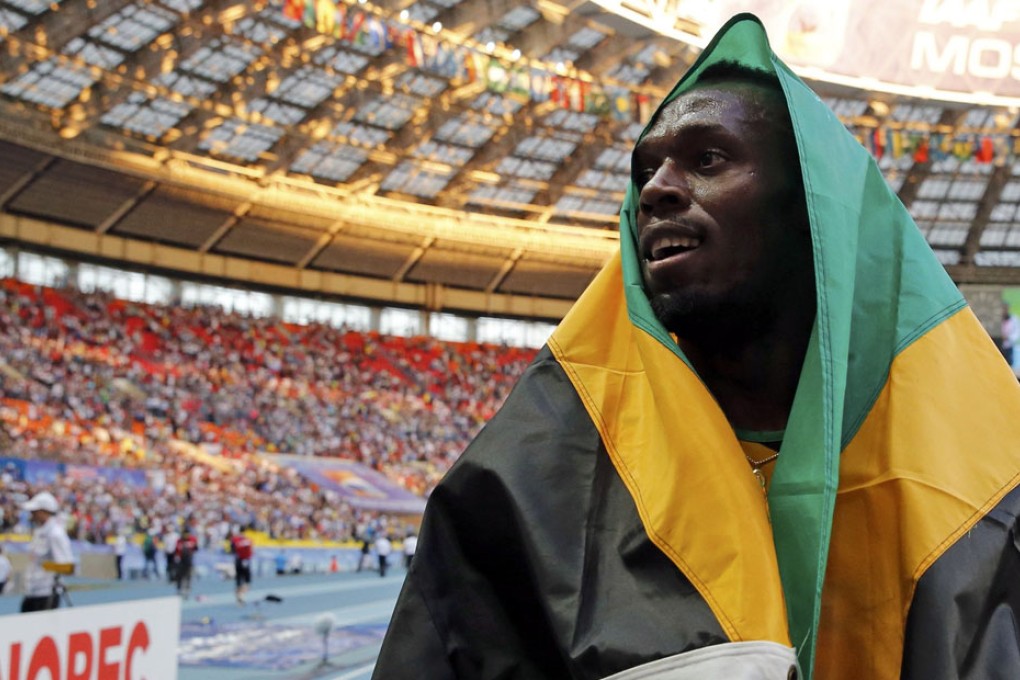 Usain Bolt drapes himself in the Jamaican flag after winning the 200 metres at the world championships. Photo: Reuters