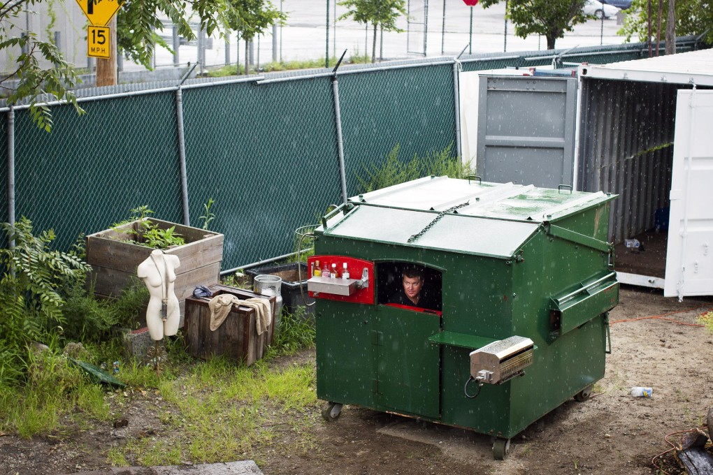 Gregory Kloehn escapes a rain shower in his "dumpster home" in Brooklyn. Photo: AP