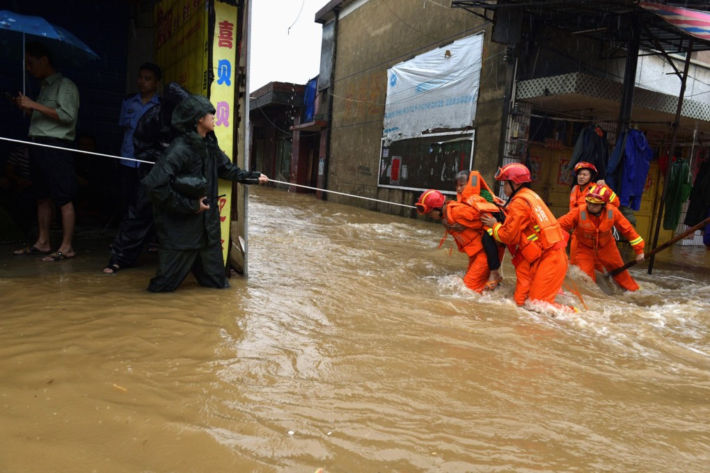 Rescuers carry a woman across a flooded street in Jiangyong county, Hunan province. Photo: Reuters