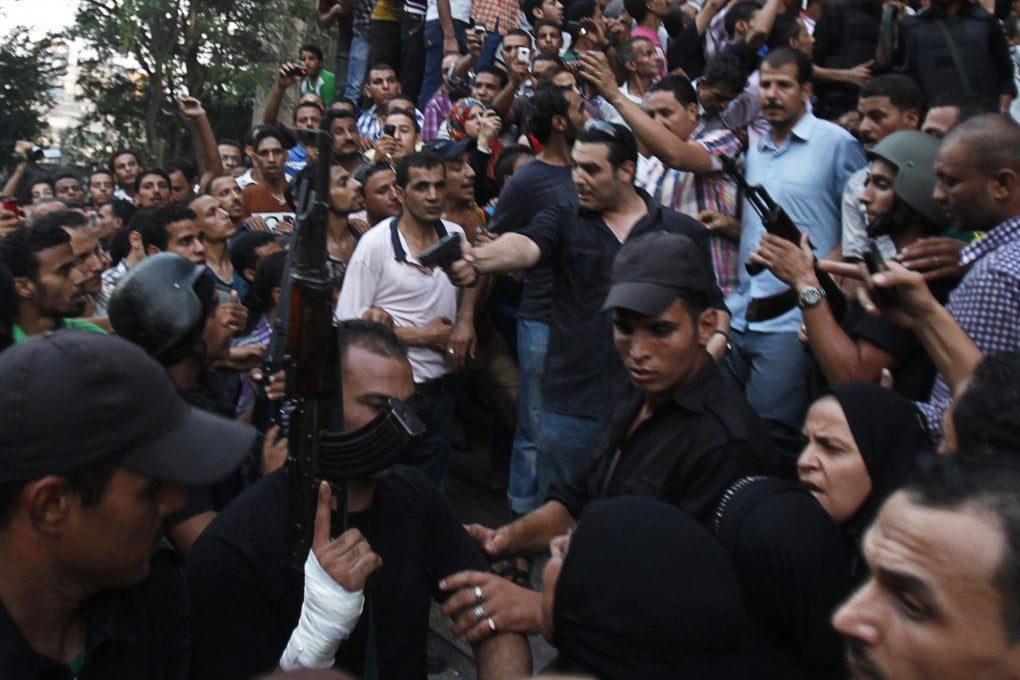 A plainclothes policeman (centre) points his gun as security forces escort Muslim Brotherhood members in Cairo. Photo: Reuters