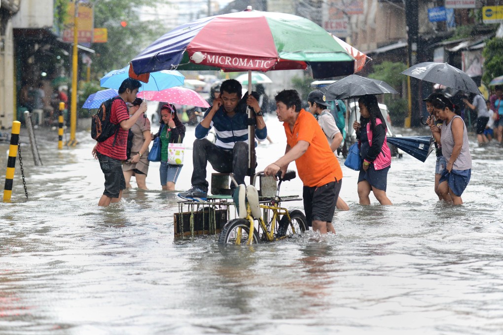 Residents wade through a flooded street in Manila. Photo: AFP