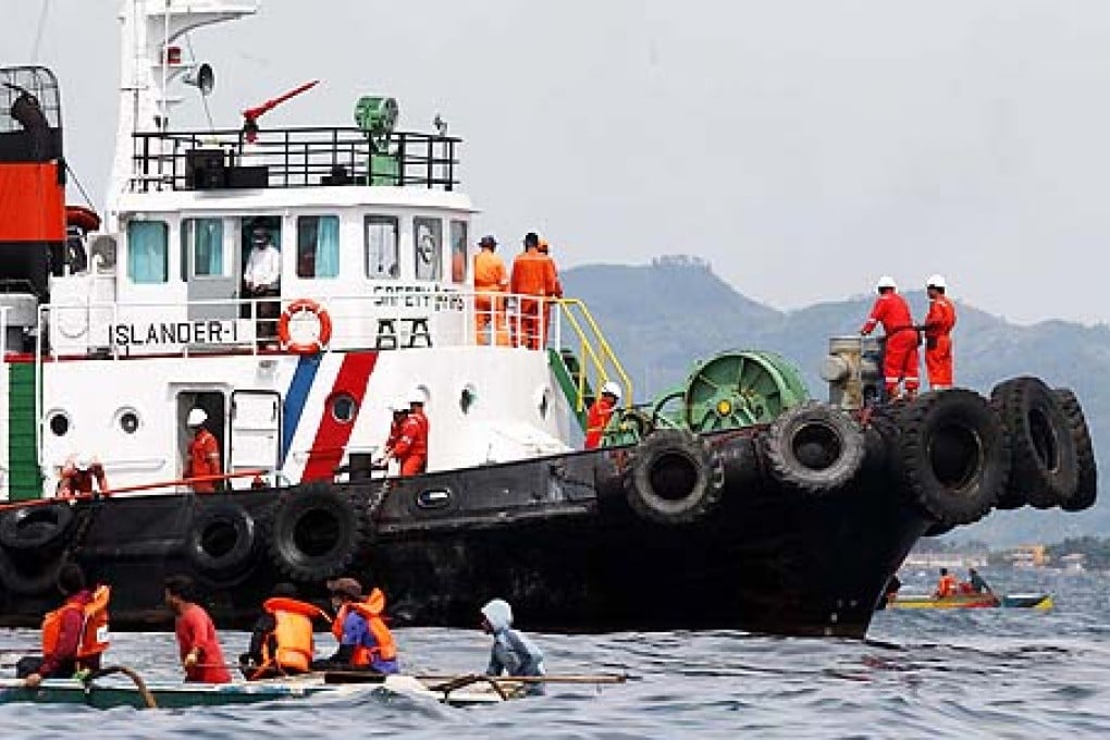 Filipino workers aboard a search and rescue vessel, spray oil dispersant chemical around the site where MV St Thomas Aquinas sank water off Cebu province, central Philippines. Photo: EPA