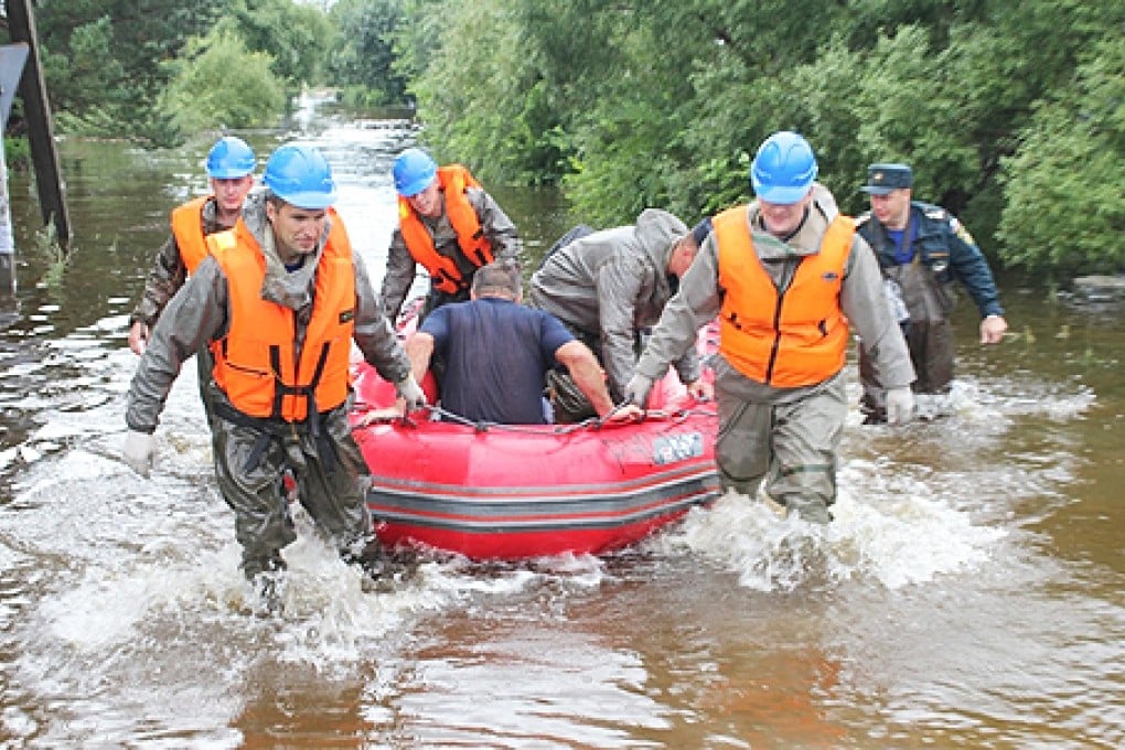 Rescue workers evacuate residents in a rubber dinghy in a flooded area of the Amur region in the far East of Russia. Photo: EPA