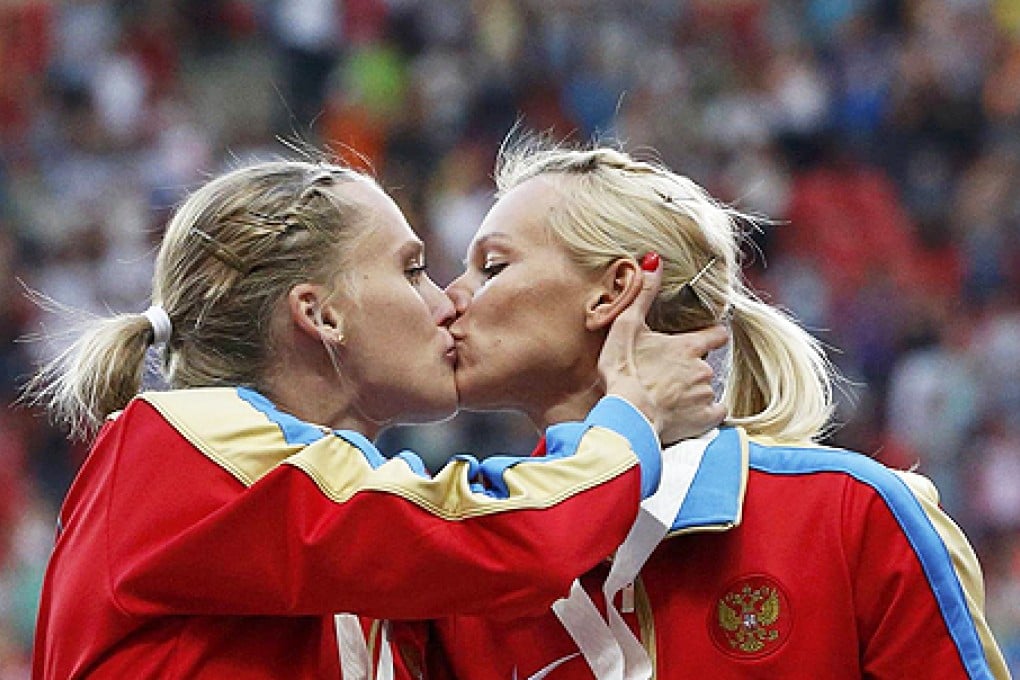 Ksenia Ryzhova kisses Yulia Guschina on the podium at the World Athletics Championships in Moscow. Photo: Reuters