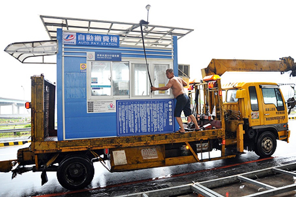 Taipei City Government engineering staff move an auto pay station booth in preparation for Tropical Storm Trami in Taipei on Tuesday. Photo: AFP