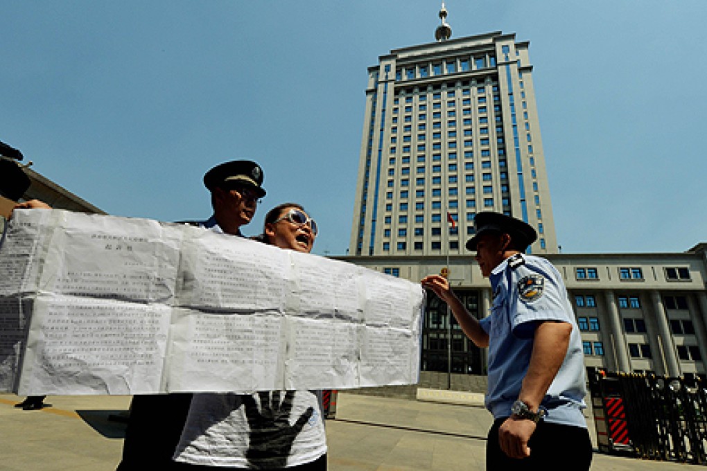 Police detain a demonstrator who was protesting against the Chinese justice system on Wednesday outside the Intermediate People's Court in Jinan, Shandong province where disgraced politician Bo Xilai will soon go on trial. Photo: AFP
