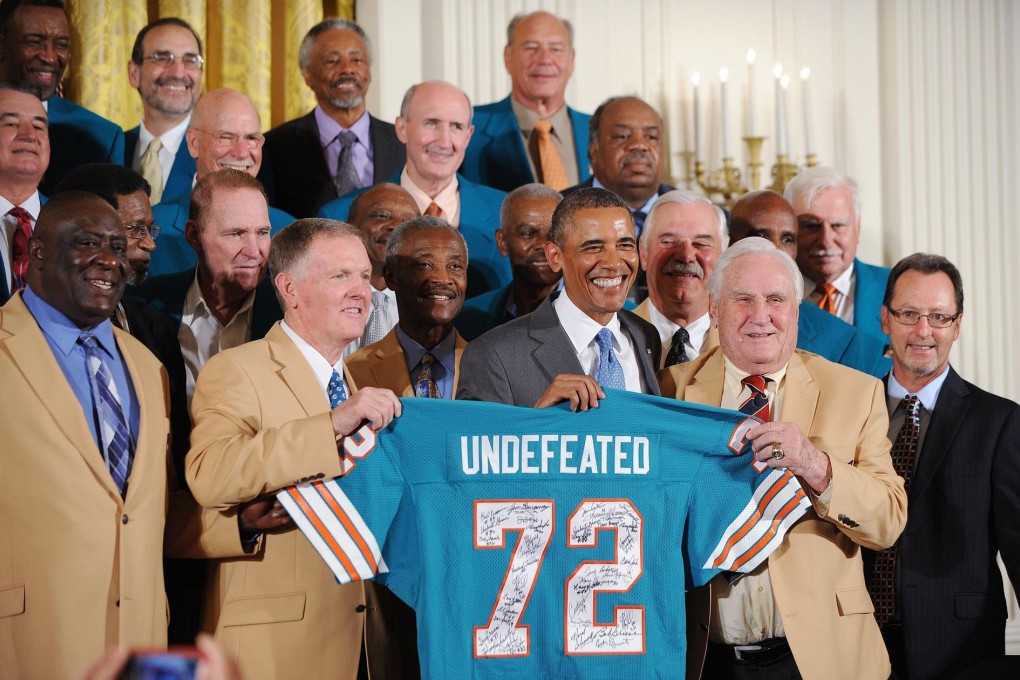 President Barack Obama holds up a jersey given to him by Miami Dolphins coach Don Shula (right). Photo: Abacausa.com