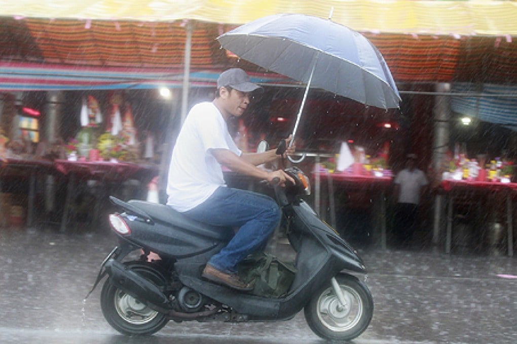 A man holding an umbrella rides a motorcycle as tropical storm Trami approaches the northeastern coastal town of Nanfangao in Ilan county. Photo: Reuters
