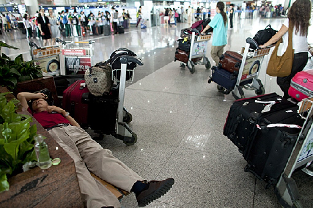 A passenger sleeps on a bench while waiting for his flight at Terminal 3 of Beijing International Airport in Beijing. Photo: AP