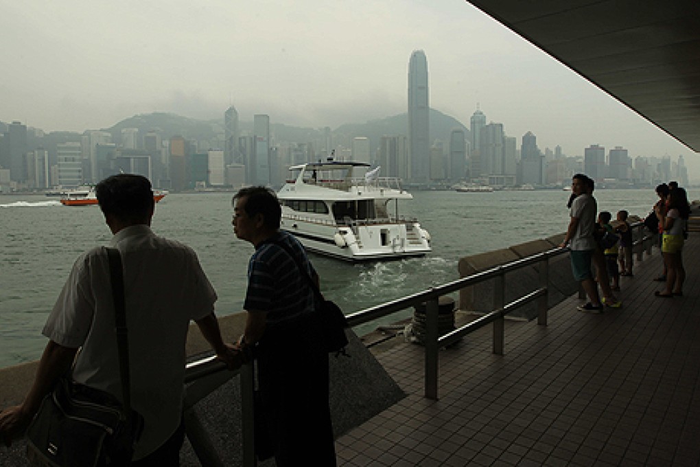 Smog shrouded Victoria Harbour wasn't a pretty picture for these pedestrians on Thursday. Photo: Edward Wong