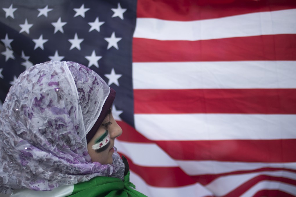 Displaced Syrian girl Malek Al Rifai stands in front of a US flag. Photo: Reuters