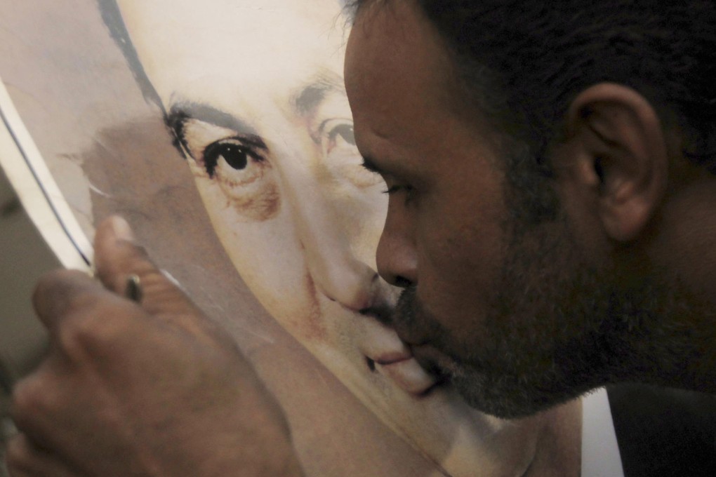 A supporter of Hosni Mubarak kisses his poster outside the Maadi military hospital in Cairo. The former Egyptian president was transferred there on Thursday. Photo: Reuters