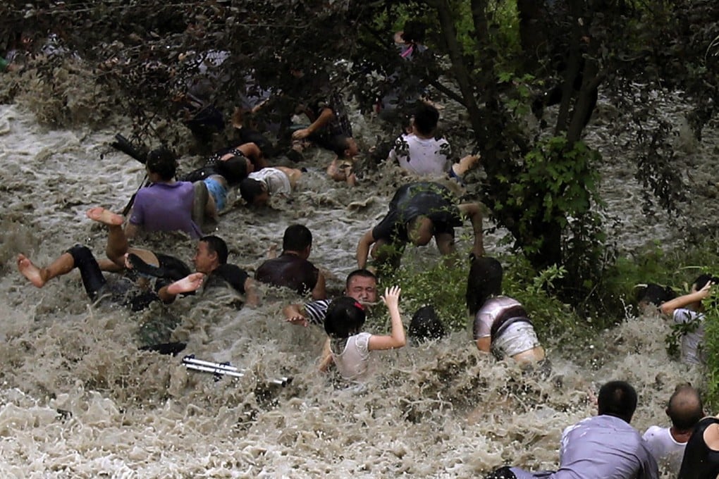 People struggle as powerful waves surge past a barrier on the banks of Qiantang River in Haining. Photo: Reuters