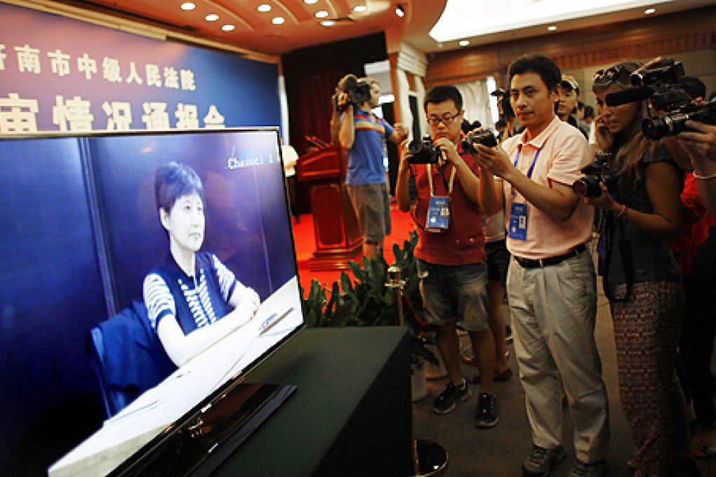 Journalists take pictures and videos of a screen displaying a video of Gu Kailai, wife of Bo Xilai, at a media room near the court where Bo's trial is being held in Jinan, Shandong province on Friday. Photo: Reuters