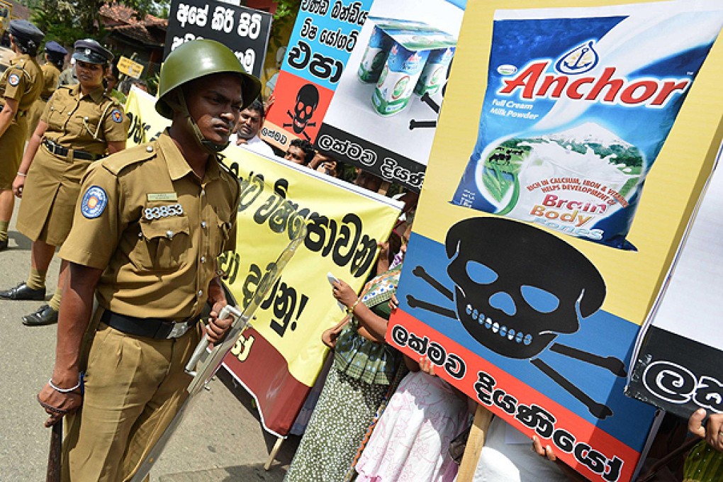 Police officers stand guard as local activists protest against alleged contaminated products in front of a Fonterra factory in Colombo. Photo: Xinhua