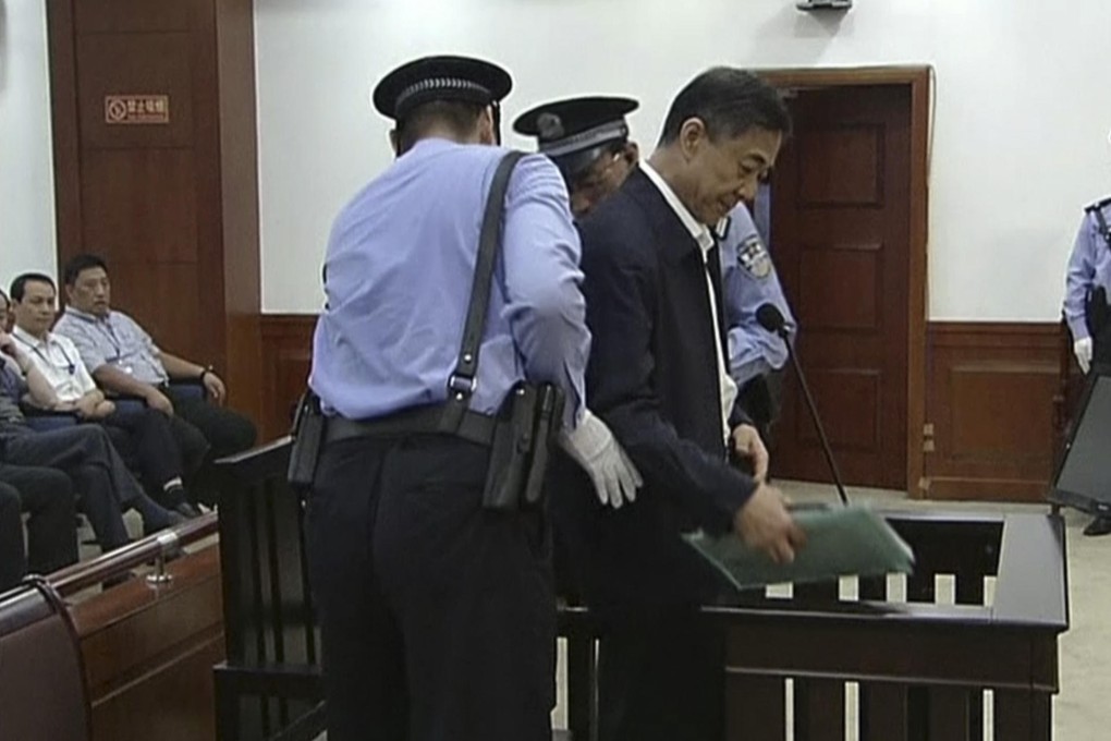 Bo Xilai, who is facing corruption allegations, is escorted to his seat by guards at Jinan Intermediate People's Court yesterday. Photo: AP