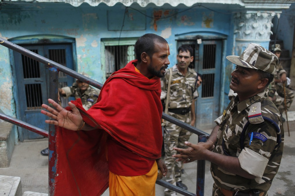 A Hindu holy man gestures as he talks to an Indian security officer deployed near a Hindu temple in Ayodhya. Photo: AP