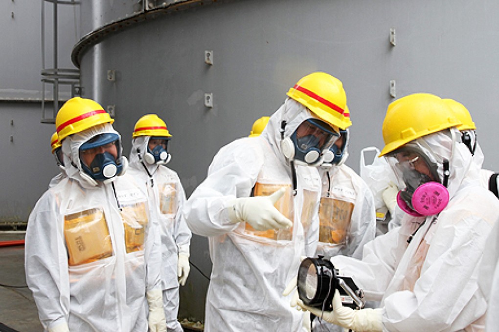 Japan Nuclear Regulation Authority members wearing protective suits and masks inspect storage tanks of contaminated water at at the Tepco Fukushima Daiichi nuclear power plant on Monday. Photo: EPA