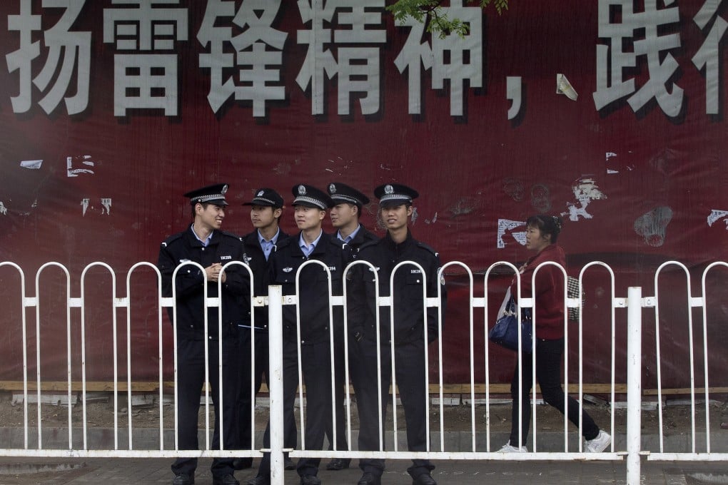 A Chinese woman walks by a troop of policemen near a clothing wholesale mall in Beijing. Photo: AP