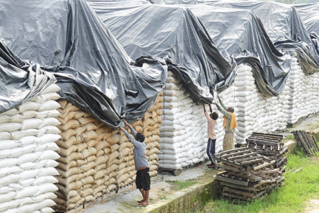 Indian workers remove plastic sheeting covering sacks of wheat at a storage facility on the outskirts of Amritsar. Photo: AFP