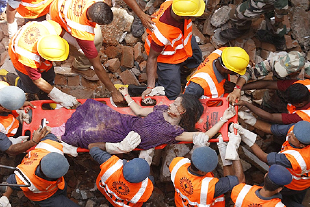 Rescue workers use a stretcher to carry a victim across the rubble after the collapse of two residential buildings in Vadodara city. Photo: Reuters