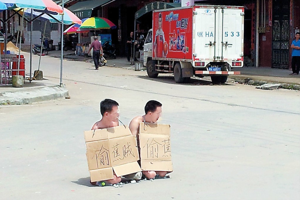 Two banana thieves were forced to kneel down in public wearing "thief" signs. Photo: screenshot via Weibo