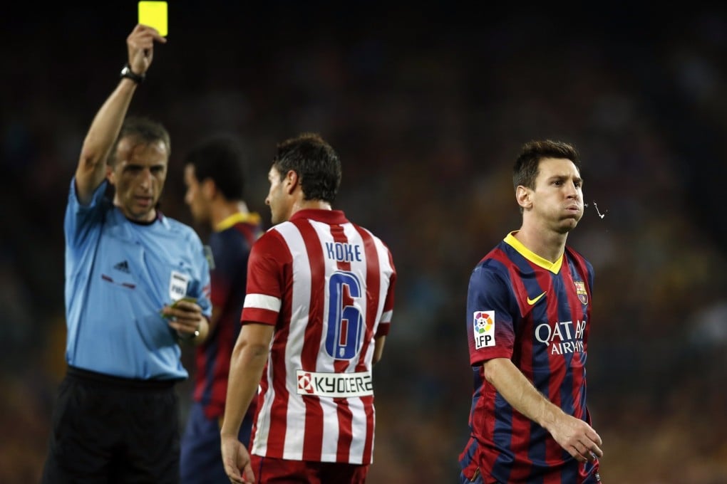 Referee Fernandez Borbalan gives a yellow card to Atletico Madrid's Koke (C) as Barcelona's Lionel Messi (R) walks away during their Spanish Super Cup second leg soccer match at Camp Nou stadium in Barcelona. Photo: Reuters