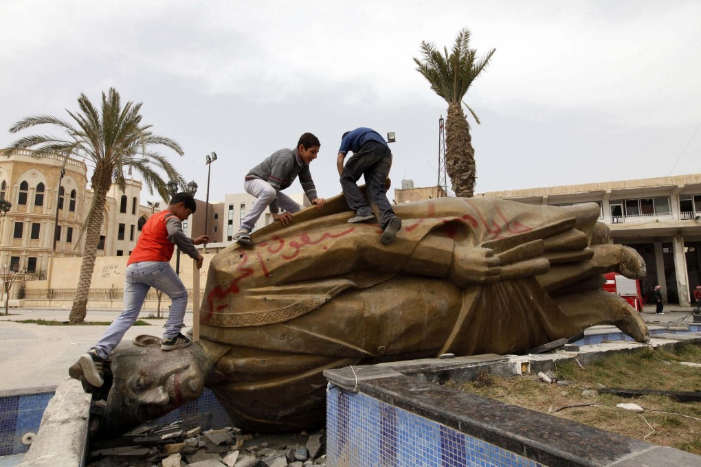 Children play on the toppled statue of President Bashar al-Assad's father, Hafez al-Assad, in Raqqa province, eastern Syria. The civil war has killed 100,000.Photos: Reuters, AP
