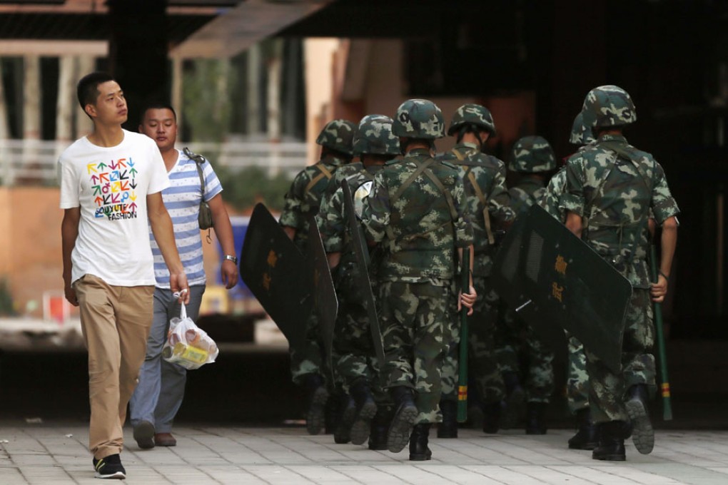 Residents walk past armed police in Kashgar. Photo: Reuters