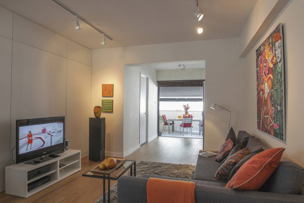 (Above & below) Living area: The Murano glass vase (NZ$65/ HK$400) was found in a charity shop in Nelson, New Zealand. The two paintings behind it are by local artist Noel de Guzman (noeldeguzman@ gmail.com). The slate grey L-shaped sofa (HK$4,000), tufted steel-tone rug (HK$1,600), black steel-and-glass side table (HK$400) and low white lacquer television console (HK$500) were bought at Ikea (various locations; www.ikea. com.hk). The silk cushions were sourced from Chatuchak market in Bangkok, Thailand, and cost HK$150 each. They are mixed with grey wool cushions (HK$350 each) from G.O.D. (various locations; www.god.com.hk) and orange cushions found at Spitalfields market in London, Britain, for £35 each (HK$425). Eckhart Liebert added a striking painting by Australian artist Gavin Brown (www.gavinbrown.com.au) above the sofa to add a splash of colour to the apartment’s neutral backdrop.