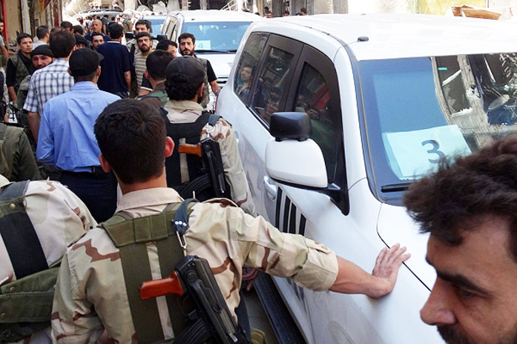 Rebel fighters and civilians surround vehicles transporting UN inspectors to the site of a suspected gas attack. Photo: AFP