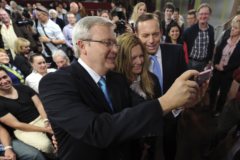 A  member of the public poses for a picture taken by Australian Prime Minister Kevin Rudd (left) next to opposition leader Tony Abbott. Photo: Reuters