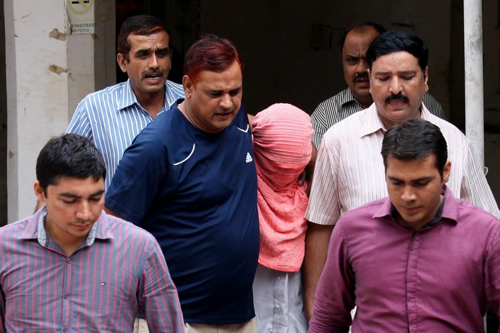 lain-clothes police escort the teenage rapist and murderer, with his face covered, out of the court after his conviction. Photo: EPA