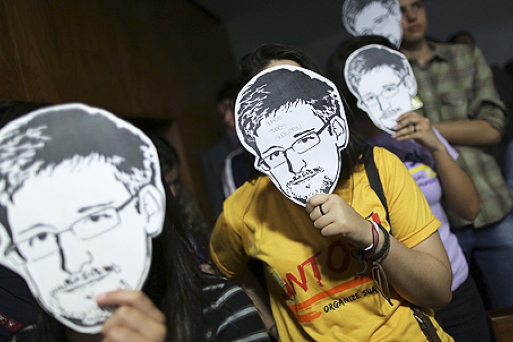 People hold up masks with pictures of former NSA contractor Edward Snowden during the testimonial of Glenn Greenwald before a Brazilian Congressional committee on NSA's surveillance programs, in Brasilia on August 6. Photo: Reuters