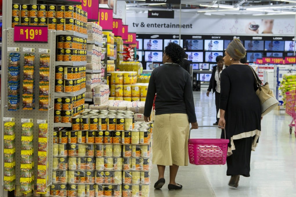 Customers carry a shopping basket inside a Game supermarket, part of Massmart Holdings Ltd., in the Fourways district of Johannesburg, South Africa. Photo: Bloomberg