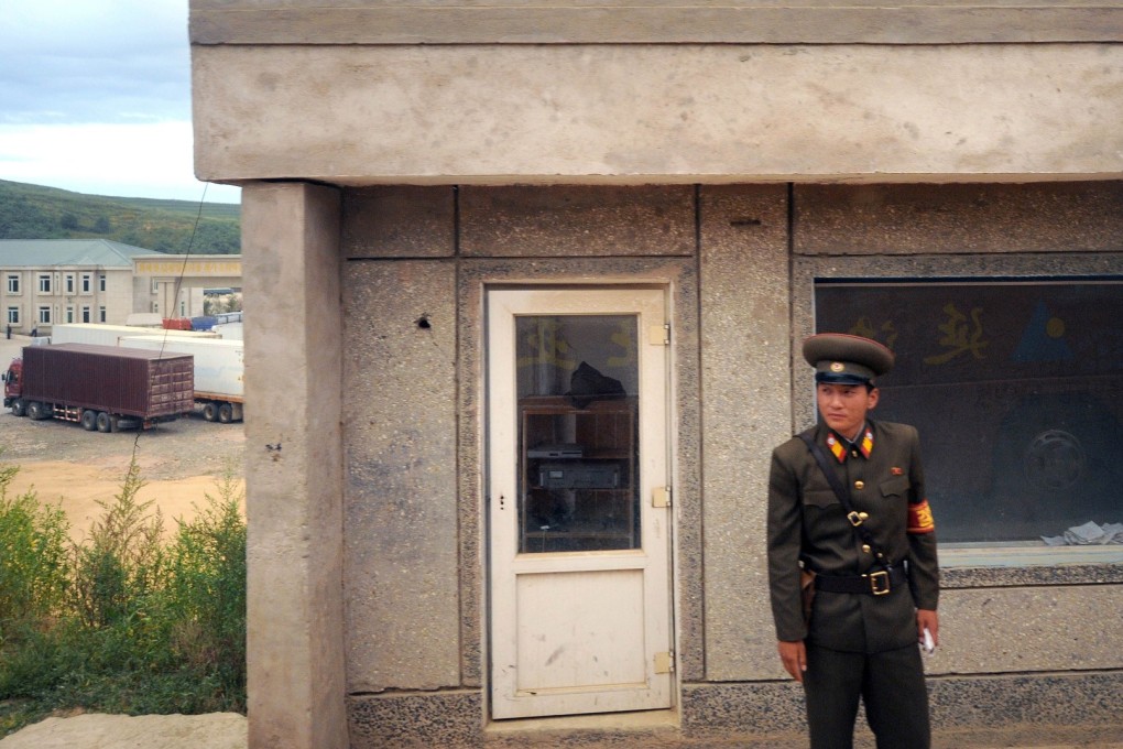 A North Korean border guard watching as tour buses pass through the checkpoint into China. North Korea is becoming increasingly reliant on China as a trading partner. Photo: AFP