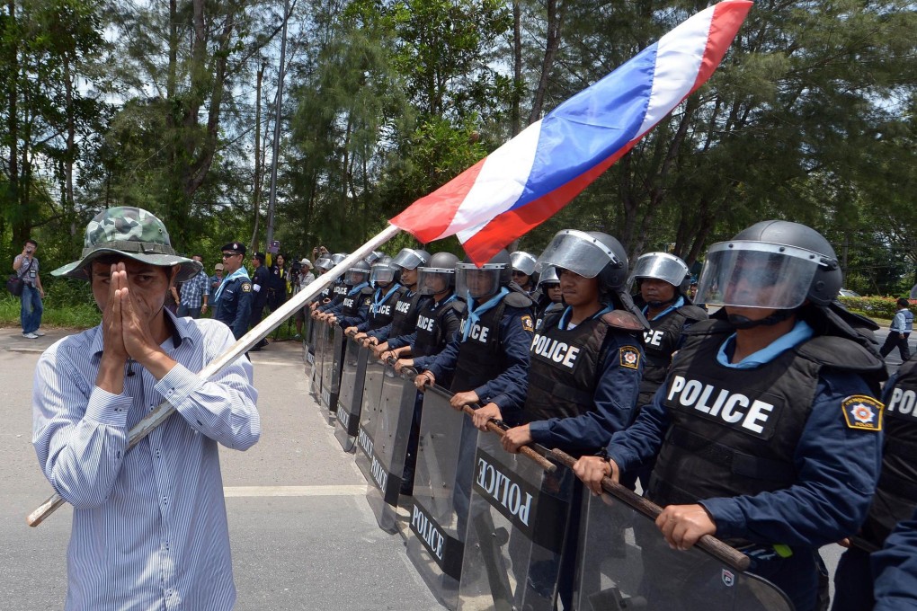 A rubber farmer gives a greeting to Thai riot police. Photo: AFP