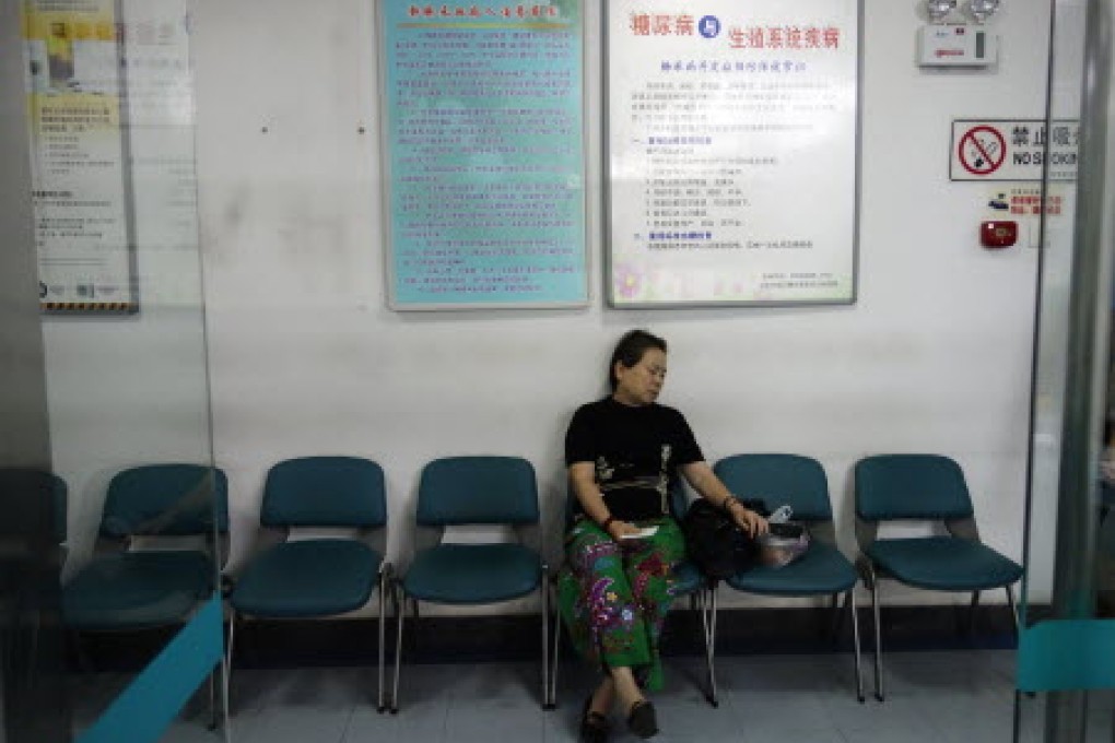 A woman waits for receiving treatment as she sits in front of a billboard showing how to avoid diabetes at a hospital in Beijing. Photo: AFP