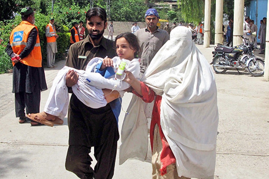 A relative carries a school girl injured after a bomb exploded at a school, outside a hospital, in Bannu, a town of militancy-hit Khyber-Pakhtunkhwa province, Pakistan, on Thursday. Photo: EPA