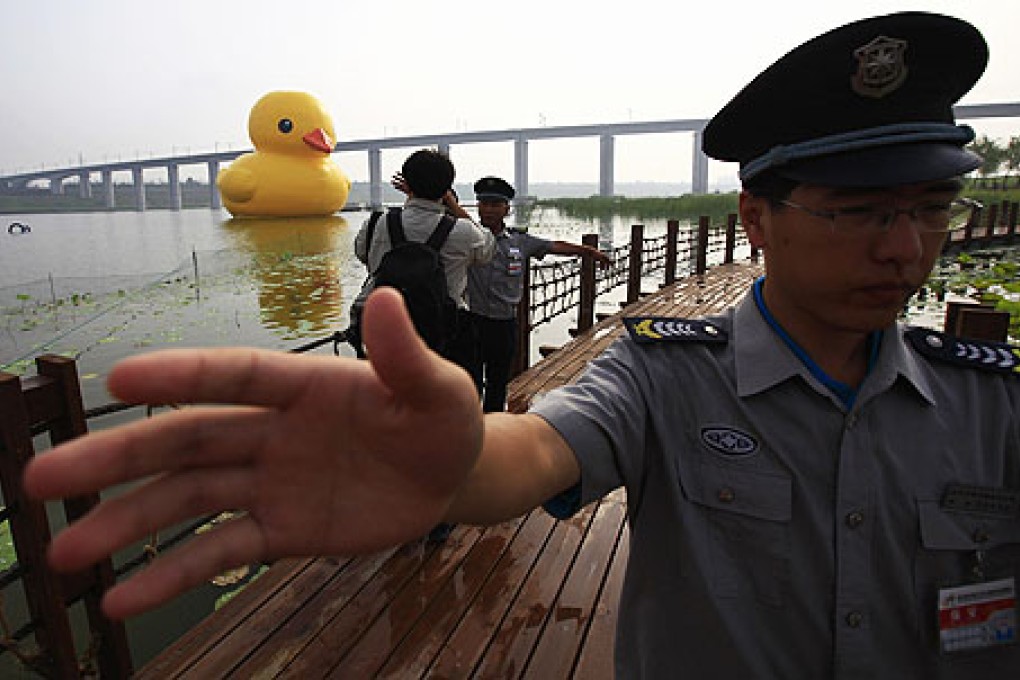 Security guards try to prevent photographers taking pictures of the inflated rubber duck created by Dutch artist Florentijn Hofman in Beijing on Sunday. Photo: Reuters