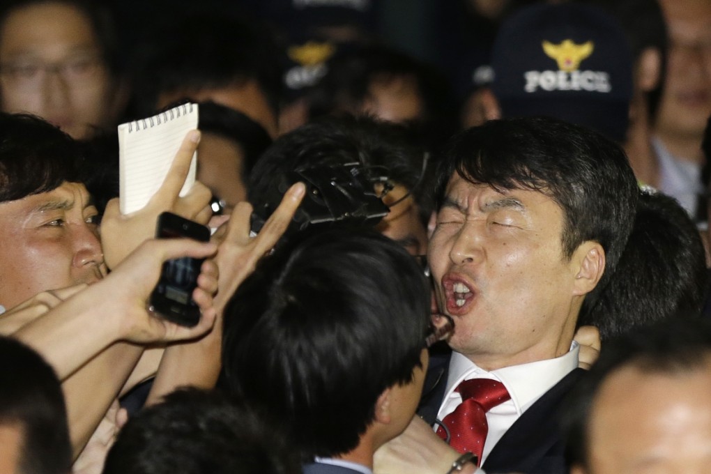South Korean lawmaker Lee Seok-ki of the leftist Unified Progressive Party, right, shouts as he is surrounded by police officers and reporters after being arrested at the Suwon police station in Suwon, south of Seoul. Photo: AP