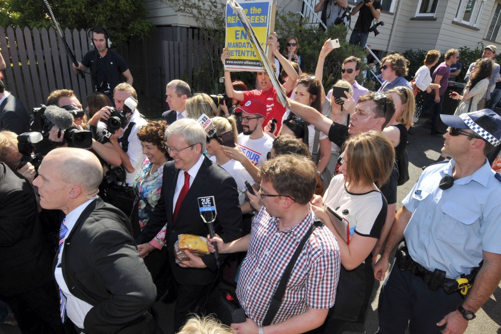 Australian Prime Minister Kevin Rudd, center, walks past protesters after casting his vote in Brisbane, Australia on Saturday. Photo: AP